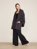 A model wearing a black CozyChic Blanket Wrap with ribbed cuffs and front patch pockets, standing on a plain background.