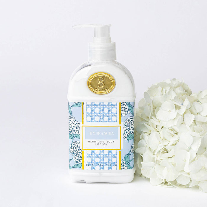 Hand and body lotion bottle with floral design next to white flowers on a light background