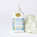 Hand and body lotion bottle with floral design next to white flowers on a light background