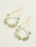 Gold hoop earrings with turquoise stones on a light background