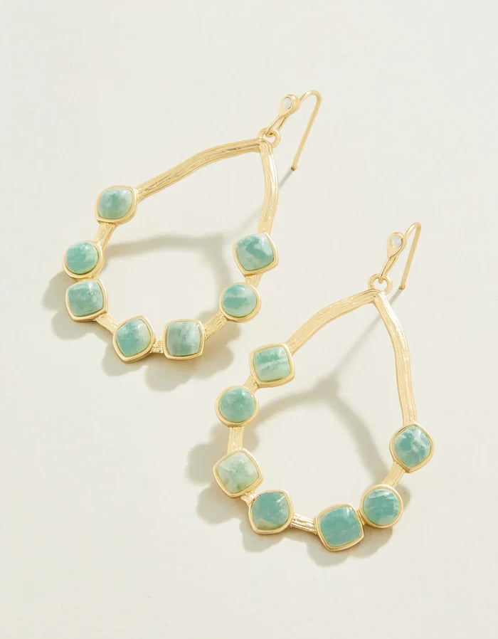 Gold hoop earrings with turquoise stones on a light background