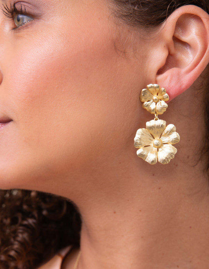Close-up of a person wearing gold floral earrings.