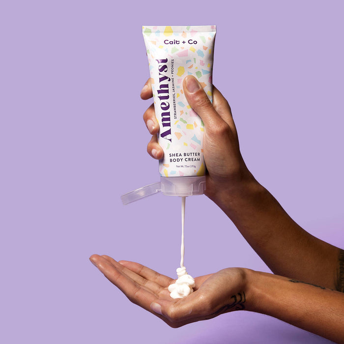 person using amethyst body cream against purple background